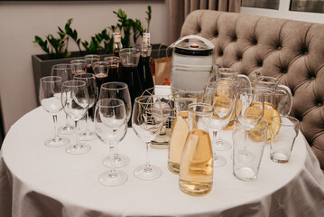 On a banquet table covered with a white tablecloth are various glasses and alcoholic and non-alcoholic drinks