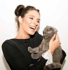 Obraz premium Pretty young woman feeling happy holding a cat and hugging it tight