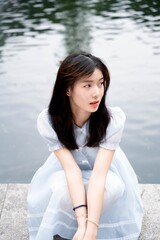 Young woman in a blue dress sitting by the water, conveying a serene and modern atmosphere.