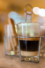 A cup of hot coffee with sweetened condensed milk served in a glass. Thai style hot coffee in vintage glass on table background
