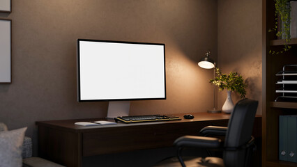 Blank screen computer under lamp light on wooden table with leather swivel chair in a dim lit room.