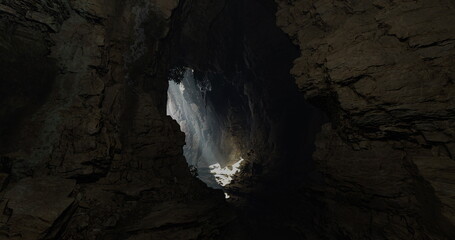 Sunlight spills into a dark cave, illuminating the rocky walls. The contrasting shadows create a mysterious atmosphere. The cave showcases impressive geological features and textures.