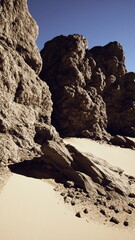 Several rocks scattered on sandy ground under the bright sun on a clear day.