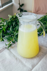 Homemade lemonade with mint, lemon and lime in a glass pitcher on the table. Refreshing drink, nutrition, healthy lifestyle