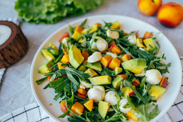 fresh salad with avocado mozzarella peach and arugula leaves served on plate. Healthy food, colorful ingredients concept, nutrition cooking wellness