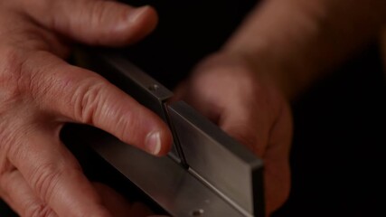 Craftsman focuses intently on adjusting a precision tool, demonstrating skilled handwork. Natural light fills the workspace, highlighting the materials and craftsmanship involved in the task.