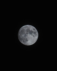 A detailed image of the full moon, focusing on its surface with clearly visible craters and texture. The photo was taken against a dark night sky, the naturalness of the Earth's satellite