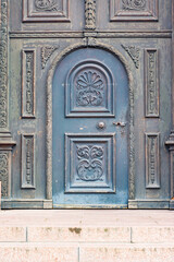 Elegant blue door with intricate carvings standing proudly against weathered wood, inviting curiosity and exploration in a historic building setting