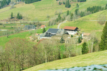 Charming rural landscape with solar panels in a tranquil valley surrounded by rolling hills and farmhouses under a clear blue sky