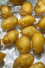 Whole Organic Raw Potatoes In Water Top View, Splash And Ripples.