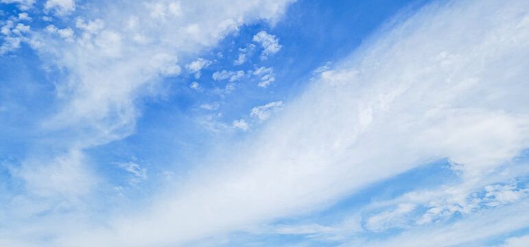 A wide-angle shot of a beautiful blue sky with soft white cirrus and cumulus clouds. Ideal for backgrounds, weather concepts, and natural themes.