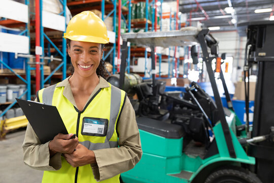 Warehouse shelves are storing cardboard boxes in brightly lit aisle, with green forklift