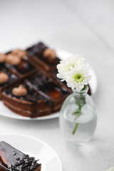 Delicious chocolate cake slices on plates with a small vase of white flowers