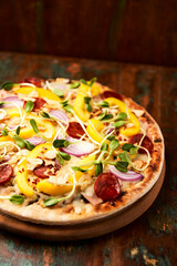 Pizza with chorizo ​​sausage, mozzarella cheese and yellow pepper. Rustic wooden background. Soft focus.	