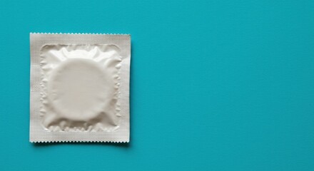 Condom on a turquoise background, symbolizing safe sex, protection, contraception, health awareness, and prevention, with ample copy space for medical or educational use