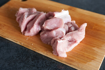 Pieces of raw turkey thigh on a cutting board, close-up
