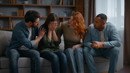 Four multiracial people home party frustrated woman friends supporting calming on couch together...