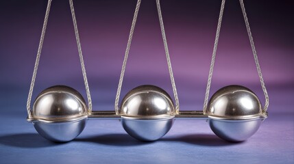 Close-up of a Newton's cradle with four metallic balls suspended on thin sts, illustrating physics concepts of motion and energy transfer