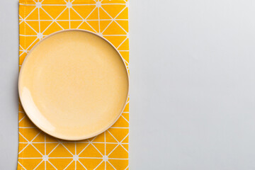 Top view on colored background empty round yellow plate on tablecloth for food. Empty dish on napkin with space for your design