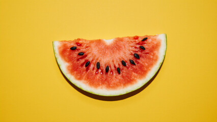 Juicy watermelon slice with seeds on a bold yellow background, emphasizing freshness and summer.