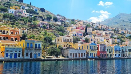 Greek island harbour with colourful hillside homes and calm turquoise water