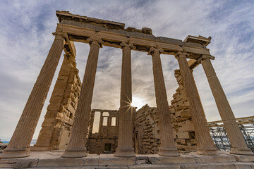 Obraz premium The Erechtheion temple on the Acropolis of Athens with sunburst behind marble columns, Greece.