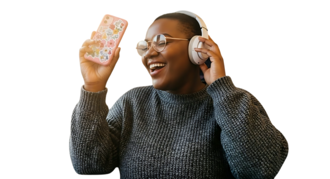 Woman smiling holding phone with floral case and wearing headphones and a gray sweater indoors looking happy
