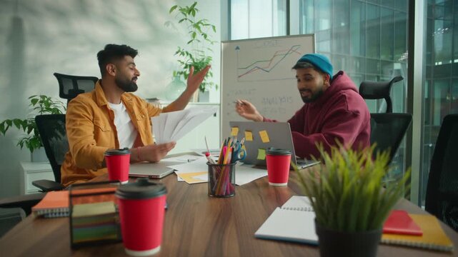 Business failure negotiation in informal office two angry talking aggressive rude Hindu men review data in paper at whiteboard finance graph quarrel confrontation Indian businessmen throwing documents
