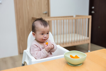 Baby eating carrot pieces during first solid meal