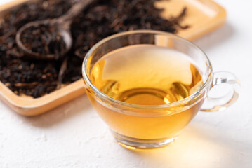 Black tea in cup glass with dried tea leaves on white background, Healthy herbal hot drink