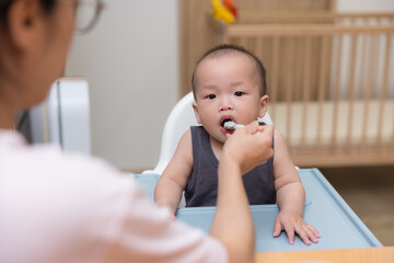 Woman give food to baby boy inside home