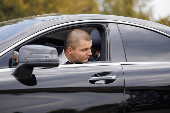 Man sitting in luxury car observing surroundings during daytime drive