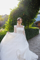 Elegant bride in a flowing white gown walking in a lush garden on a sunny afternoon