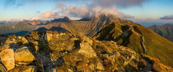A sweeping golden sunset panorama captures the rugged ridge of Salatín (2,047 m), its rocky slopes bathed in warm light, clouds gathering over peaks, looking out across the Western Tatras’ dramatic al
