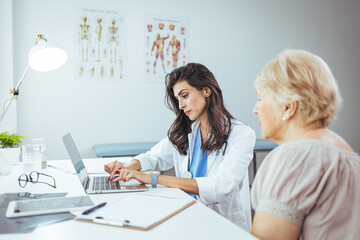 Obraz premium Doctor Using Laptop While Consulting With a Senior Patient in a Clinic