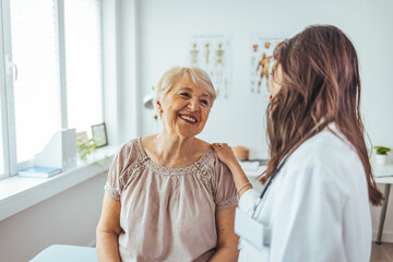 Fototapeta premium Friendly Interaction Between Doctor and Elderly Patient in Bright Clinic Room
