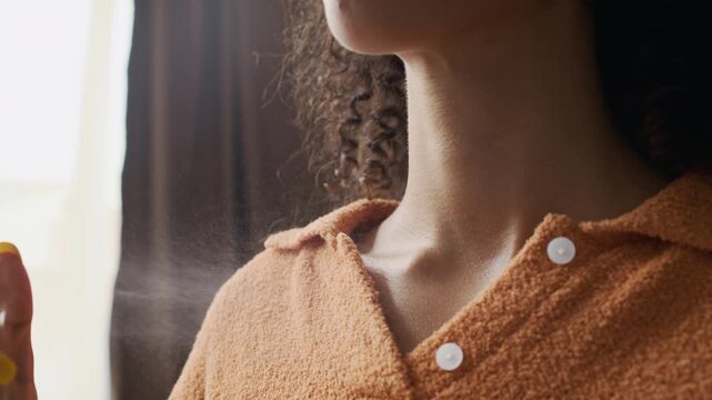Closeup of unrecognizable young woman applying perfume on her neck as part of her beauty and grooming routine, preparing with style and confidence before date, event, or outing