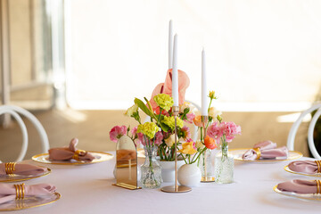 Table decor in a restaurant with beautiful vases of pink anthurium flowers, roses and carnations....