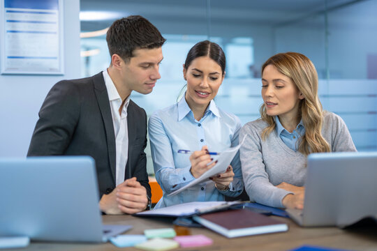 Female colleague explaining report to her business team while they listen attentively during a meeting in a beautiful blue office