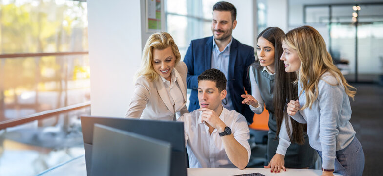 Business team collaborating on project around computers during office meeting