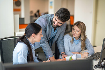 Obraz premium Manager presenting report to two female colleagues seated at computers