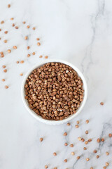 Buckwheat in a bowl on a white marble table. Top view.