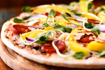 Pizza with chorizo ​​sausage, mozzarella cheese and yellow pepper. Rustic wooden background. Soft focus.	