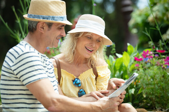 couple of tourist sitting on a park bench using city-map - Powered by Adobe