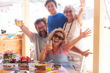 Happy Multi generation family share brunch together in a sunny day. Festive table with a colorful mix of vegetables and fruit for a healthy eating.