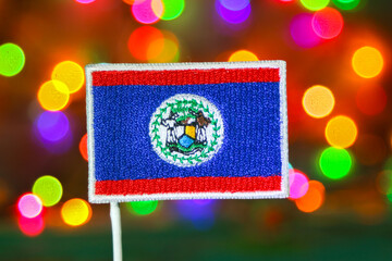 Belize flag embroidery with colorful bokeh fireworks background, symbolizing New Year celebration in Belize City with festive and patriotic spirit.