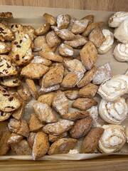 Assorted Homemade Cookies on Parchment Paper, Traditional Italian Pastries, Freshly Baked Sweets with Powdered Sugar, Rustic Dessert Display, Top View, Bakery and Food Concept
