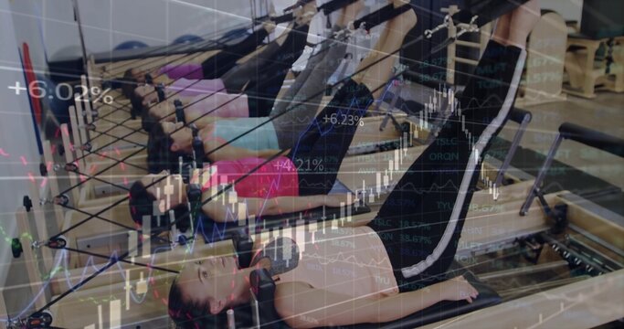 Six women in activewear doing Pilates leg presses in Pilates studio, with reformer machines