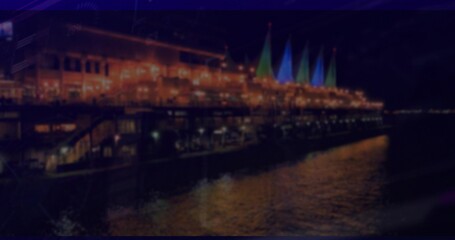 Glowing pier-side restaurant with string lights and sail structures, reflecting water patterns