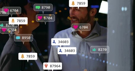 Smiling business colleagues chatting on balcony at night, with floating social media notifications